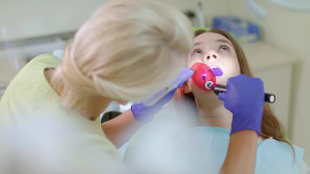 Dentist working with dental polymerization lamp in oral cavity. Teeth treatment