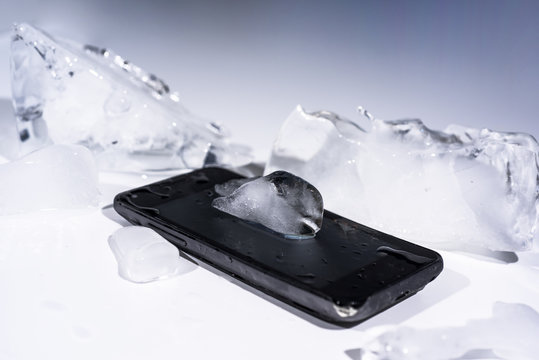 Black smartphone frozen in ice. Abstract object photo