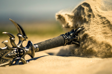 Accessories of a knight isolated on the sand during the day. Conceptual image. Sand is spreading.