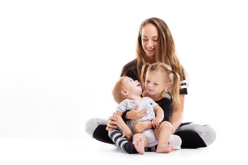 Concept of healthy happy family. Mother is sitting on floor with two cute children isolated at...