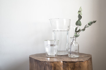 Nice still life and decoration with glass jar of water and eucalyptus plant in a wood small table