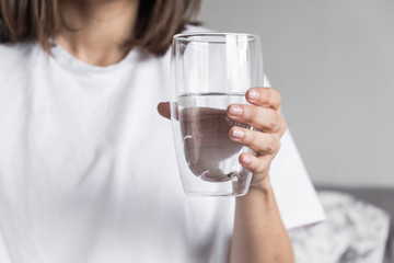 Beautiful charming woman drinking a big glass of water and wearing white clothes