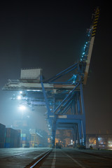 container terminal in industrial port with cranes.  Sea port container terminal during work at night in fog