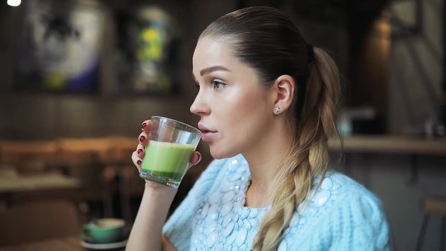 Woman drinking matcha latte in cafe
