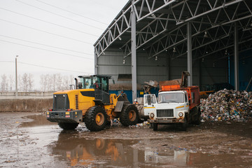 A special machine unloads the garbage and the bulldozer works on the waste dump site at the waste disposal plant. Technological process. Business for sorting and recycling.