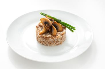 Buckwheat with mushrooms in a plate on a white background