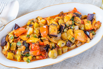 Italian cuisine - caponata on a plate on a rustic background
