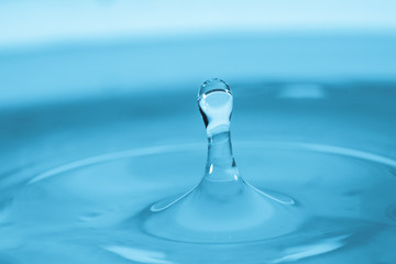 Fototapeta na wymiar Water drop splash in a glass blue colored