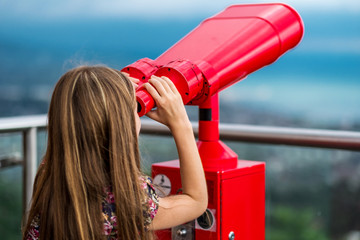 Young girl using a tower viewer to look at panoram of city