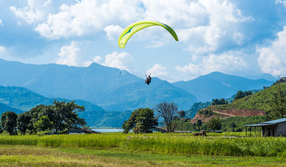 paraglider that flies over meadow, Pokhara region, Nepal. Himalayas mountains on the background.
