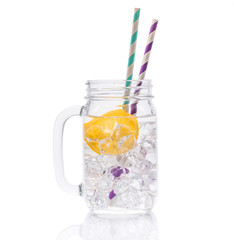 Ice water with lemon and straws in glass jar isolated on a white background