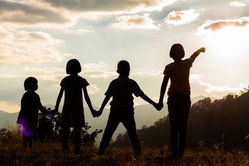 Group children standing looking sunset on mountain