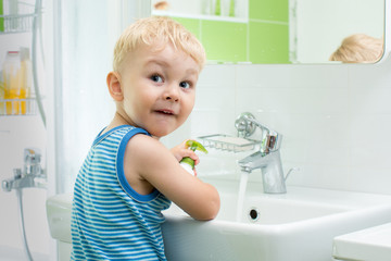 child boy washing his face and hands with soap in bathroom