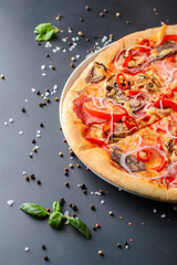 Half of italian pizza and fresh basil leaves on a dark backgroud, close up. Traditional italian cuisine