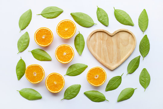 Top view of orange fruits  and  green leaves with wooden heart shaped plate isolated on white background.