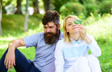 Couple bearded man and woman enjoy nature while sit on green grass meadow. Nature beauty concept. Woman enjoy relax nature background. Pure nature. Couple with green leaf relax natural environment