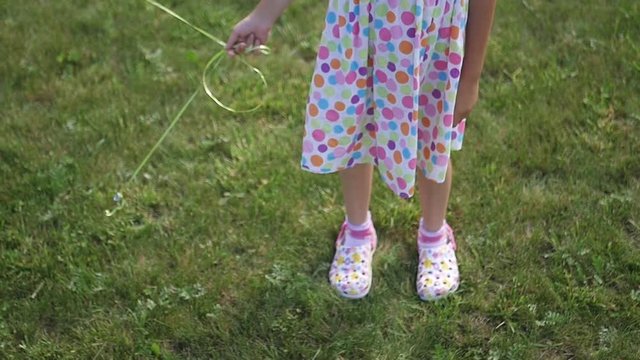 A little girl in a dress in bright circles is standing on the green grass. slow motion, 1920x1080, full hd