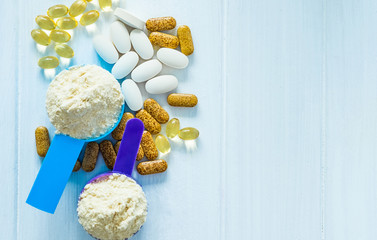 Closeup blue and purple measure dishes with protein powder and white-yellow sport pills around on...