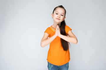 Girl on a gray background folded his hands at his chest.