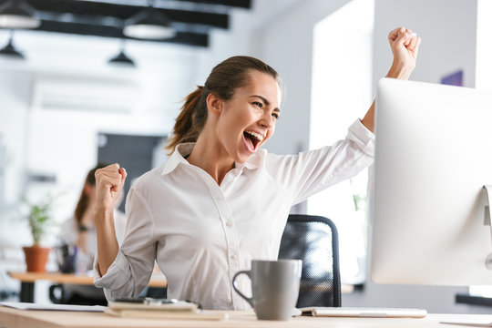 Happy Excited Business Woman In Office Working With Computer Make Winner Gesture.