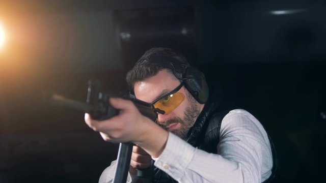 Person aiming with a rifle at a range, close up.
