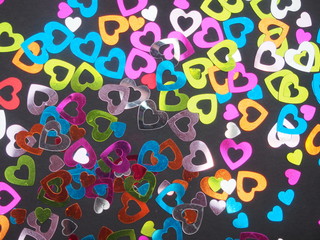 Colorful shiny hearts on a black background. Hearts are arranged randomly.