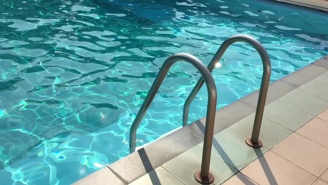 Grab bars ladder in the blue swimming pool