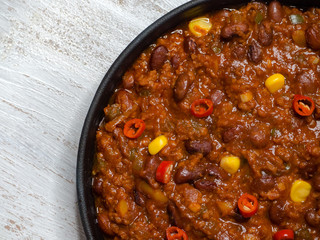 Texas chili. Chili con carne in frying pan on white wooden background. 

