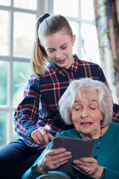 Teenage Granddaughter Showing Grandmother How To Use Digital Tablet