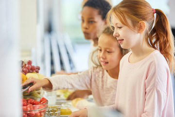 Schüler in Grundschule nehmen Obst vom Büffet