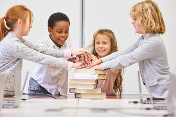 Gruppe Kinder in Grundschule stapeln Hände zur Motivation