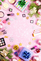 Make up cosmetics, presents and Christmas decorations on artistic pink background, copy space