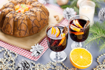 Christmas cake, two glasses of hot mulled wine with sliced orange. Christmas background with food and decorations.