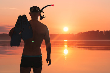 An athletic man with a swimming mask, snorkel and flippers enters the lake. He is going to do freediving. © Happyphotons