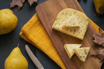 Cheese with herb in a cutting board on dark background.