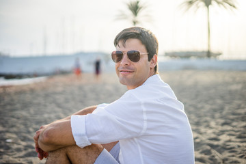 Portrait of handsome man sitting relaxed on the beach