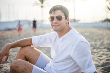 Fototapeta na wymiar Portrait of handsome man sitting relaxed on the beach