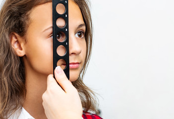 Oculist examines teenage girl with diagnostics equipment in ophthalmologic clinic
