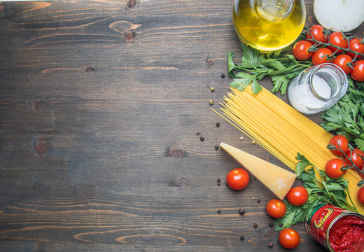 cooking vegetarian pasta with cherry tomatoes, parsley, onion and garlic, butter, tomato paste and cheese, on a rustic wooden background, place for text