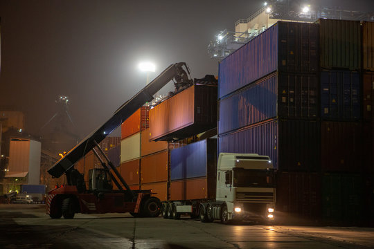Reach Stacker during operation. Reach-stacker container loader during night work. Industrial port container terminal