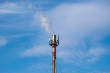 Obraz premium Chimney of an industrial plant. Smoke goes straight from the chimney to the blue sky