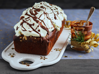 Chocolate loaf cake decorated with whipped cream frosting and melting chocolate. Christmas and New Year celebration concept.