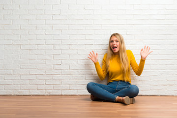 Young girl sitting on the floor with surprise expression because not expect what has happened