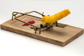 Closeup of a mousetrap rigged with a yellow cheese doodle