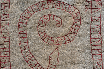 Close up of an old rune stone with red runes in the shape of a snake