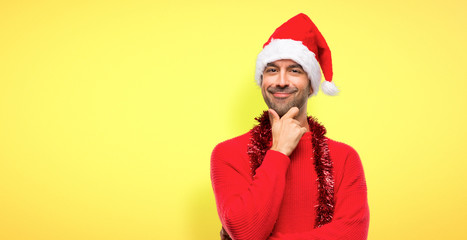 Man with red clothes celebrating the Christmas holidays smiling and looking to the front with confident face on yellow background