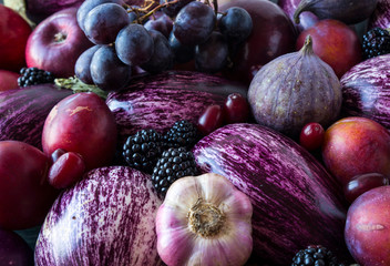 Background of fresh vegetables and fruits. Purple eggplant, blackberries, plums, grapes, figs, apples, grape and garlic. Top view. Purple food.