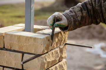 The worker is laying bricks on the fence
