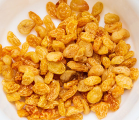 Yellow raisins in a plate as background