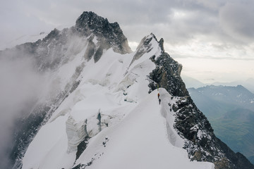 Climbers or alpinist on a knife sharp ridge of an alpine peak or summit of Aiguille du Rochefort....